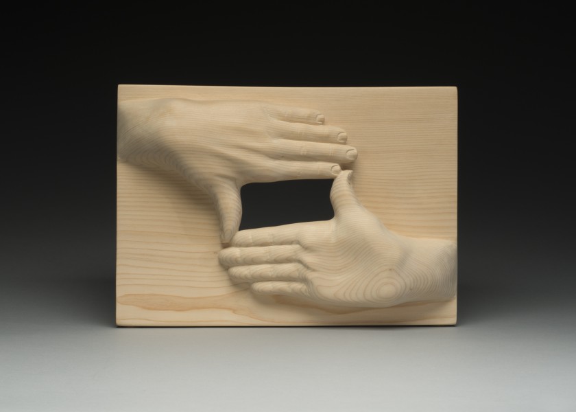 wood carving of 2 hands forming a window